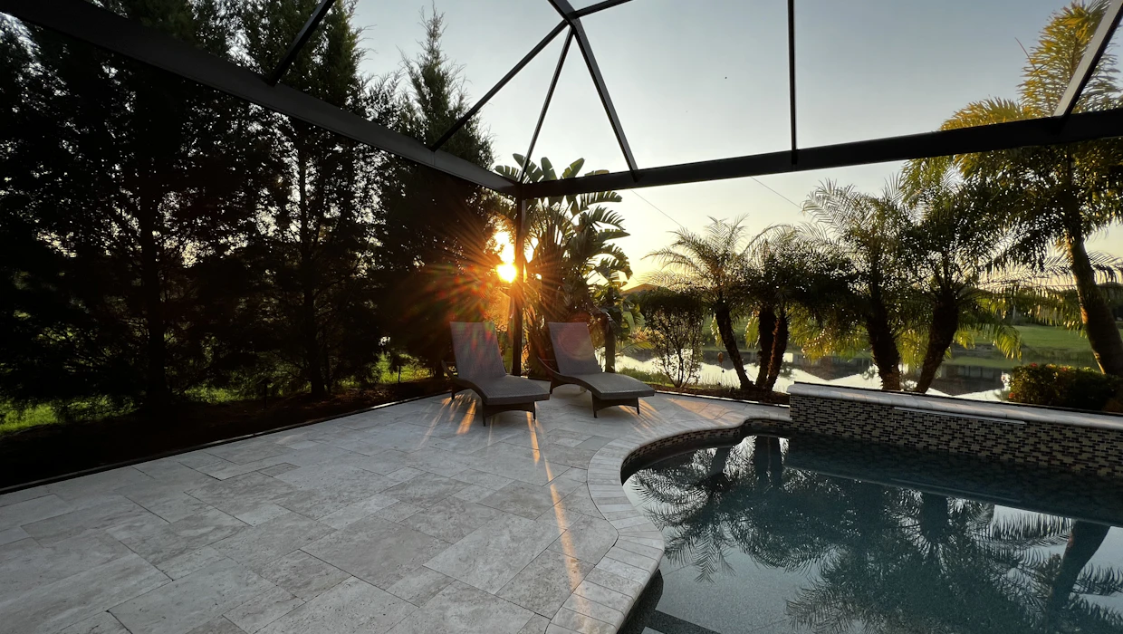 Aluminum pool cage with taut charcoal screen over a backyard pool in bright Florida sun