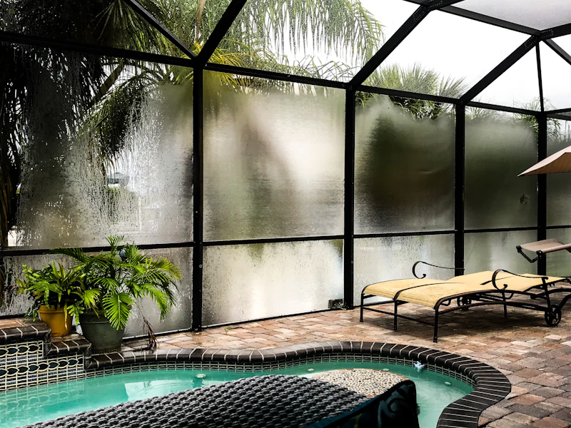 Aluminum screen enclosure roof framing against a clear blue sky